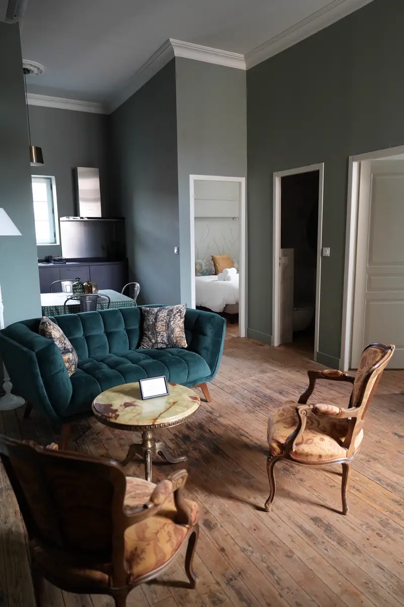 Salon de l'appartement Mazarin : canapé en velours vert, fauteuils anciens et table en marbre
