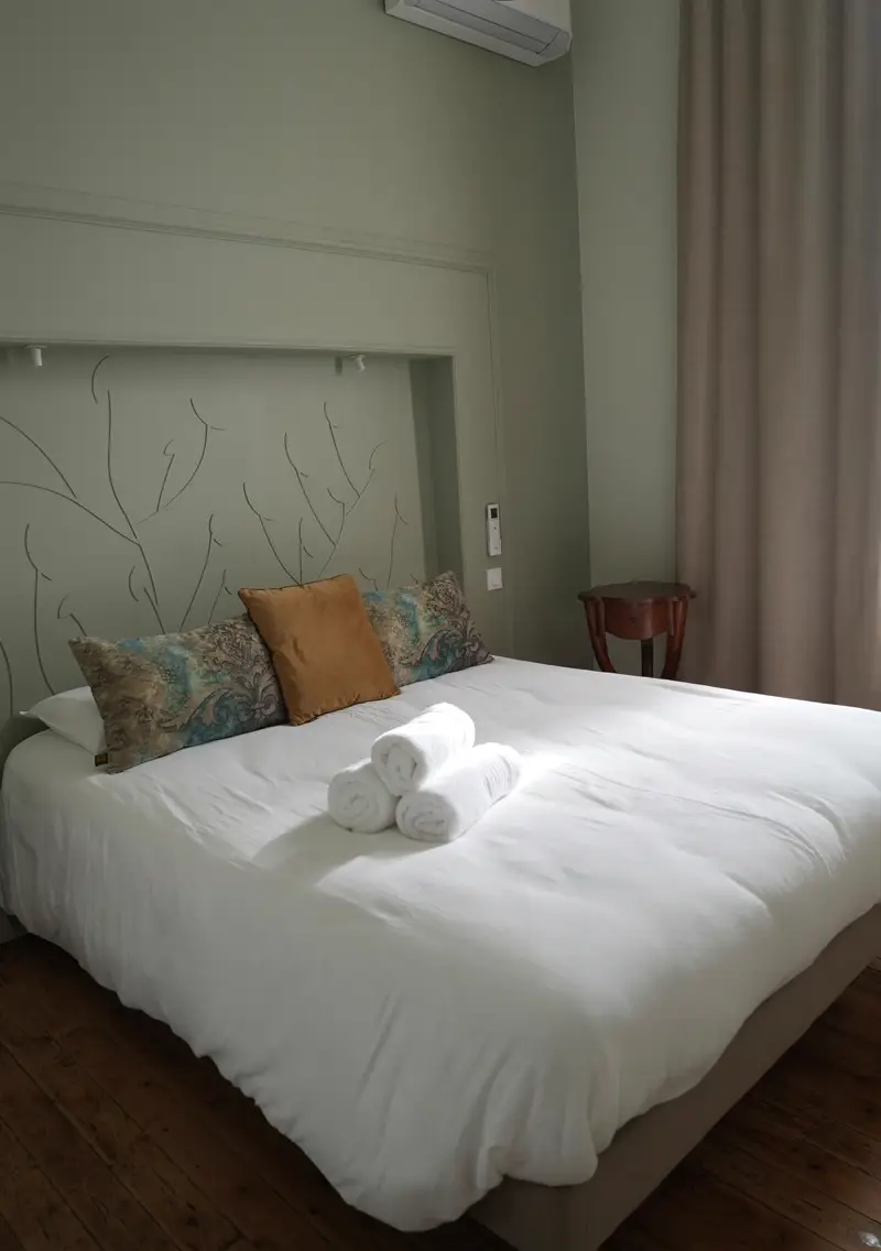 Chambre de l'appartement Mazarin : lit double, tête de lit peinte à la main et murs vert sauge