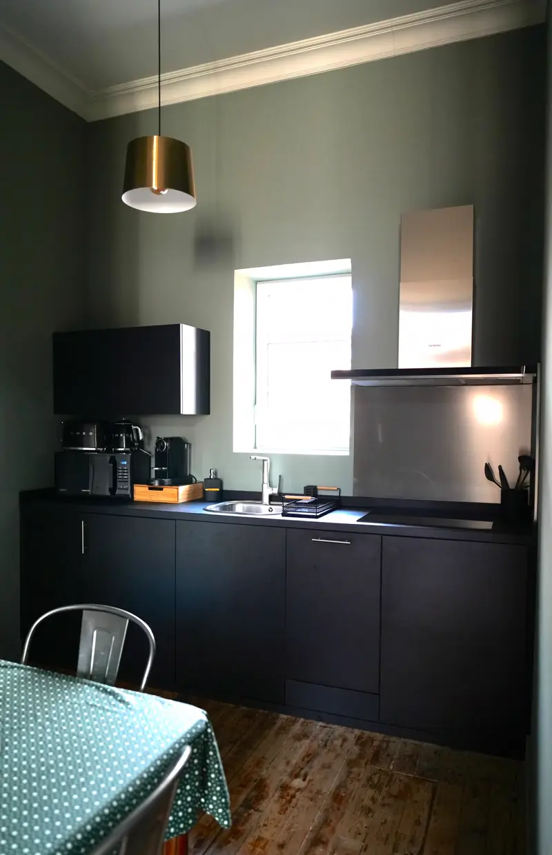 Cuisine équipée noire de l'appartement Mazarin avec hotte inox et table de repas